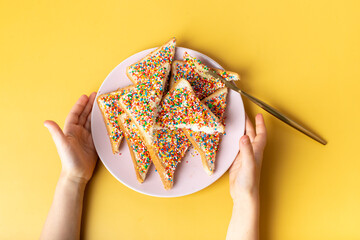 Fairy bread in hand. The famous traditional Australian food Fairy Bread on a yellow background