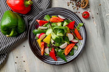 Vegetable salad with tomatoes and cucumbers and bell pepper on grey wooden table top view