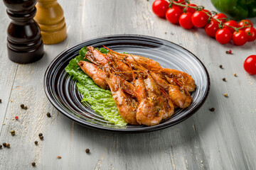 Roasted shrimps with lemon and greens on plate on grey wooden table