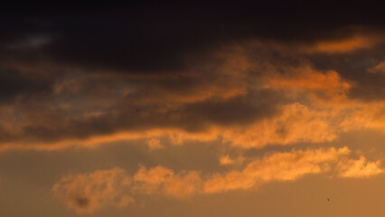 Crépuscule orangé, sous un ciel partiellement couvert