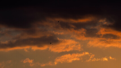 Crépuscule orangé, sous un ciel partiellement couvert