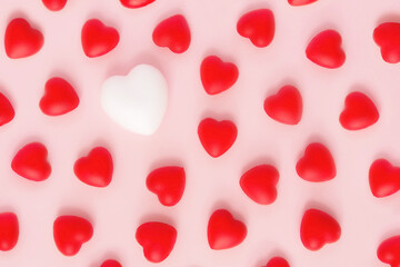 Red hearts pattern with one white heart on pink backgrounds. Symbol of love, affection, anniversary. A minimal concept of happiness, fulfillment, togetherness. Valentine's Day.