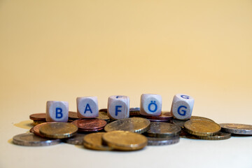 Wooden blocks with the word BAFÖG on pile of coins, BAFÖG concept background, closeup