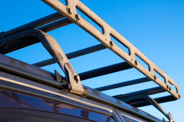 Metal trunk on the roof of the car against the blue sky. Homemade car trunk rails.