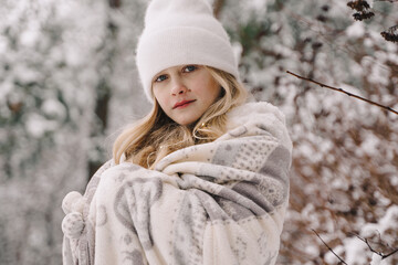 Beautiful girl in a white sweater in a white hat. Girl in a snowy forest
