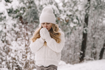 Beautiful girl in a white sweater in a white hat. Girl in a snowy forest