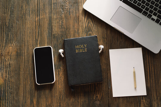 Study Bible worship online concept. Church online Sunday new normal concept. Bible, cell phone and earbuds on a wood background. Home church during quarantine coronavirus