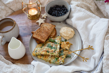 A cozy breakfast in bed set up with coffee, candle, & neutral setup