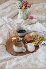 A cozy breakfast in bed set up with coffee, candle, & neutral setup
