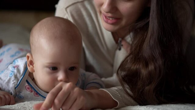 Newborn Active Baby With Young Mom. Cute Smiling Teethless Face Portrait Early Days On Stomach Developing Neck Control. Woman With Child Look At Camera Reed Book. Infant, Childbirth, Beginning Concept