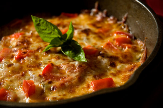 Pizza In Cast Iron Skillet With Fresh Basil Garnish