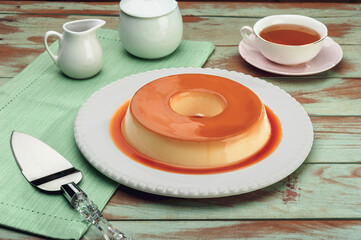 Milk pudding with caramel syrup on a white plate.