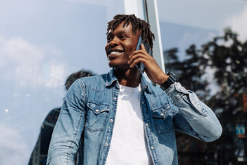 Image of a handsome smiling African man talking on his cell phone while walking on a city street