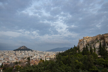 Obraz premium View of the city of Athens November 17, 2021: Evening landscape, blue sky with clouds, soft light. Picturesque view from the hill to the old town.