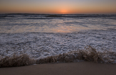 ocaso con las olas rompiendo en la orilla de la playa