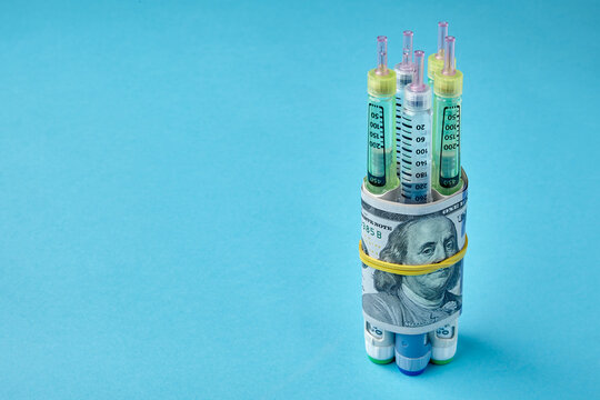 nsulin syringe pens wrapped in dollar bills on a blue background