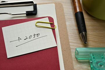 A piece of paper clipped to the edge of the red notebook has 2050.