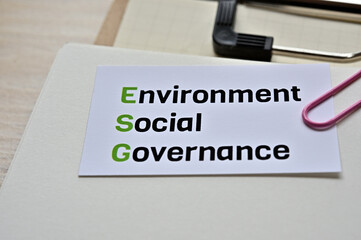 A piece of paper clipped to the edge of the notebook has Environment, Social, Governance.