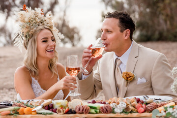 Bride and Groom drinking rosé wine at romantic picnic 