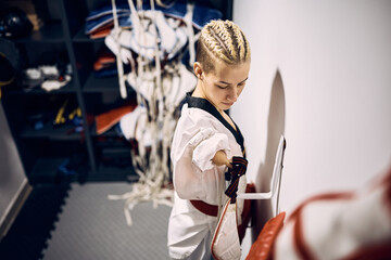 Taekwondo fighter with para-ability getting ready for sports training in dressing room.