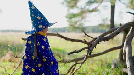Fantasy child in wizards robe in forest. Kid play magician outdoors. Girl, kid, plays in wizard...