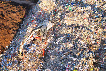 Landfill with Construction and Demolition waste (CDW). Trash disposal for recycling and re-use. Excavator working on industrial landfill. Recycling of building waste materials. Secondary raw.