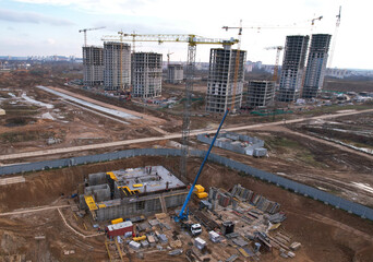 Сonstruction site with foundation pit for monolithic reinforced skyscraper. Monolithic slab foundation and concrete pouring. Tower crane on building construction. Mobile auto Crane on formworks.