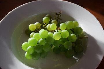 Juicy green grapes in the afternoon sun on a table top