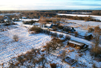 Wooden home in village in winter season. Country houses in countryside in snow. Suburban house at countryside. Aerial view of roofs with snow of with rural homes in winter. Old Russian wooden houses.