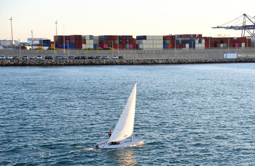 Sailboat at sea on sailing on the waves. Yachtsman during training on a sailboat. Skiff and Sailboat in sea port near the Spanish coast. Sail sport in Yacht club. Sail boat on waves on sunset in sea. 