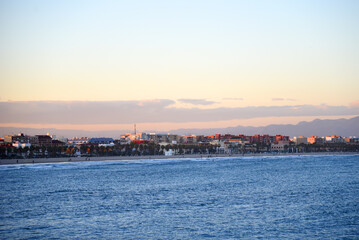 View on coastline and beach from La Marina de Valencia on the sea to the Las Arenas beach, Playa de las Arenas, Platja del Cabanyal and Playa de la Malvarrosa. Waves at sea on sunset.