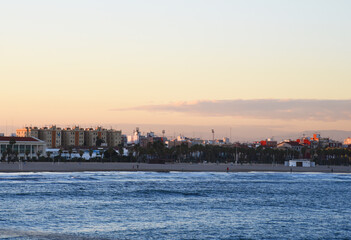 Fototapeta premium View on coastline and beach from La Marina de Valencia on the sea to the Las Arenas beach, Playa de las Arenas, Platja del Cabanyal and Playa de la Malvarrosa. Waves at sea on sunset.