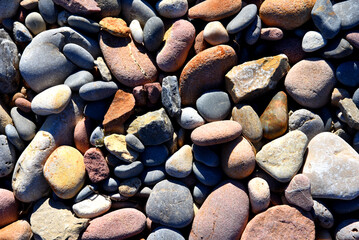 Stones on beach. Decorative texture of stones. Sea stones background. Colored stone on coastline..