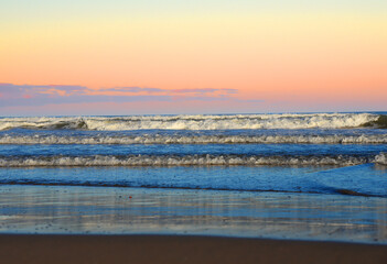 Waves at sea on dramatic sunset background. Waves at sea during storm and wind. Wave from the sea goes on land to the beach. Splashing Waves in ocean, background, texture. Wave at Rising Storm.