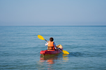 man in life jacket paddling a kayak boat in sea
