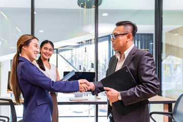Asian business CEO congratulate female employee for the outstanding achievement of her team performance by shaking hand in the modern office workplace
