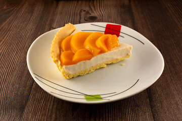 slice of peach cheesecake on a plate on a wooden table
