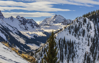 Beautiful view of Aspen, Snowmass mountain range, Colorado, USA, in winter; peaks are covered with snow and pines; blue sky with clouds in background - Powered by Adobe