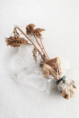 Bouquet of dried sunflower flower wrapped in paper and cellophane on a white background.