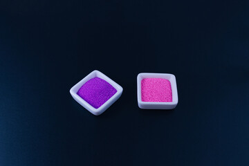 Two white square trays filled with multicolored sand