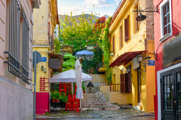 Fototapeta na wymiar A colorful hillside alley in the Plaka district of Athens, Greece, with cafes and shops at the base of the ancient Acropolis.