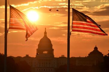 United States National flags and capitol building in silhouettes during sunrise - Washington D.C.  United States