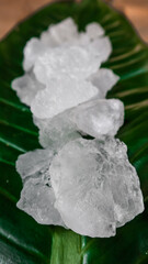 Crystal clear alum cubes or Potassium alum on green leaf. Chemical compound substance. Concept for beauty , spa and underarm treatment industrial. 