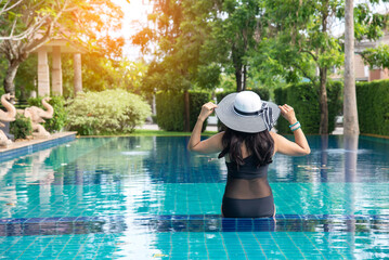 beautiful young asian woman relax smile around outdoor swimming pool in hotel resort nearly sea...