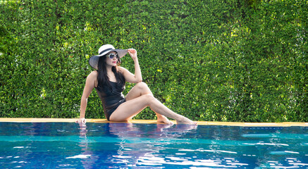 beautiful young asian woman relax smile around outdoor swimming pool in hotel resort nearly sea...