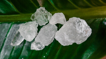 Crystal clear alum cubes or Potassium alum on green leaf. Chemical compound substance. Concept for beauty , spa and underarm treatment industrial. 