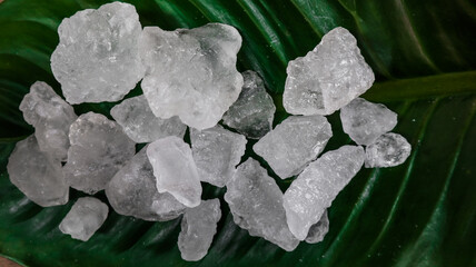 Crystal clear alum cubes or Potassium alum on green leaf. Chemical compound substance. Concept for beauty , spa and underarm treatment industrial. 