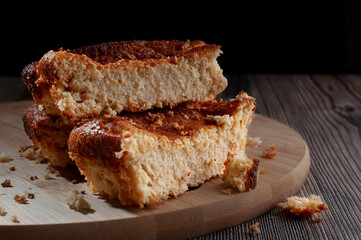 Home made pieces of corn cake on a round wooden cutting boardwith a black background