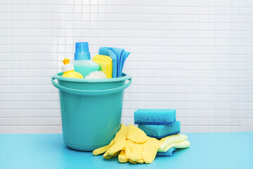 Cleaners and detergents in bucket, accessories for cleaning various surfaces and rooms blue background