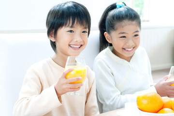 オレンジジュースを飲む男の子と女の子